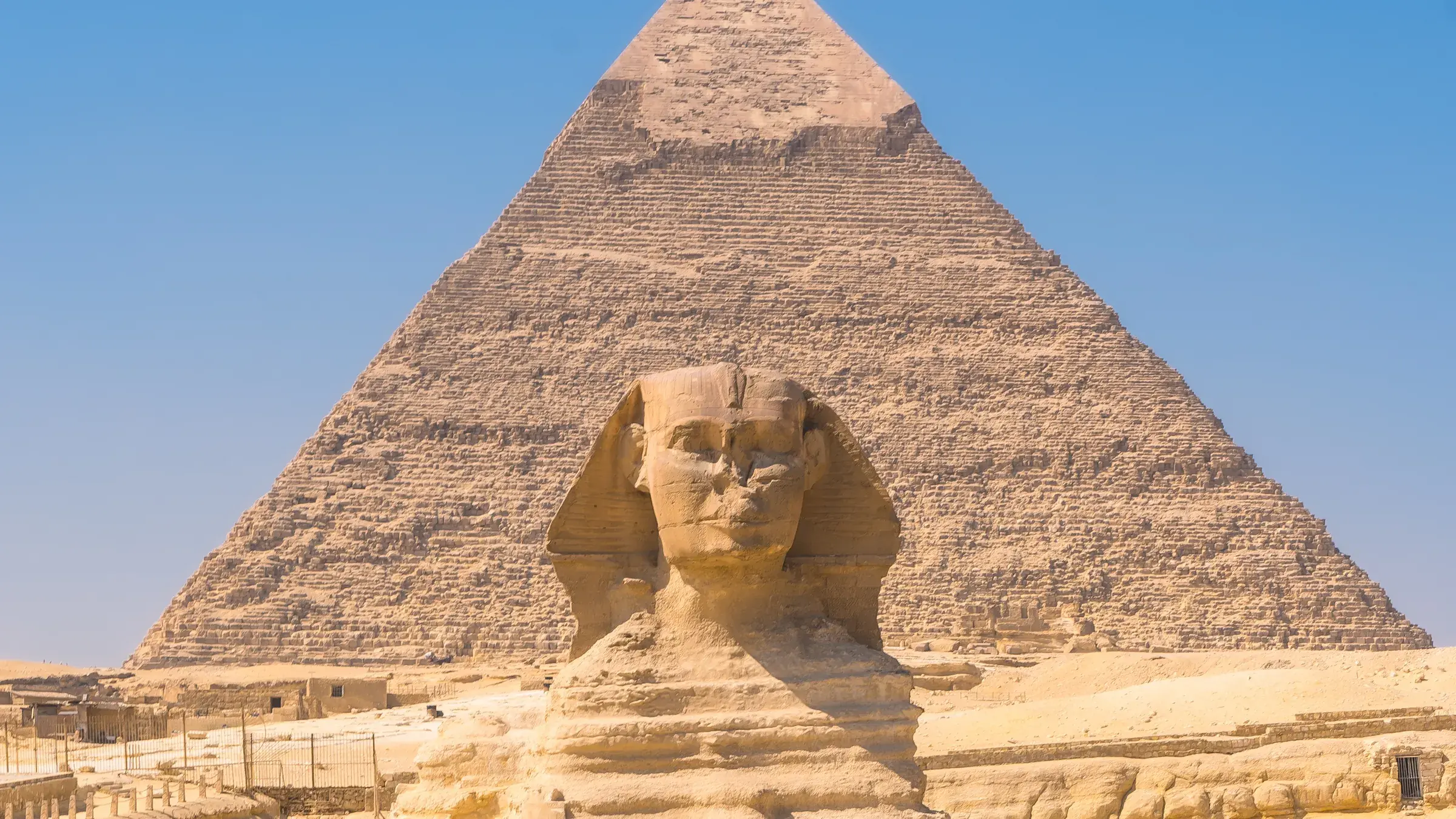 Die Große Sphinx von Gizeh, dahinter eine der Pyramiden
