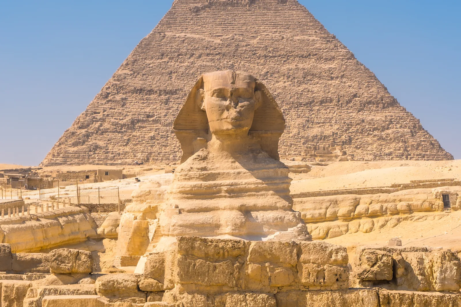 Die Große Sphinx von Gizeh, dahinter eine der Pyramiden