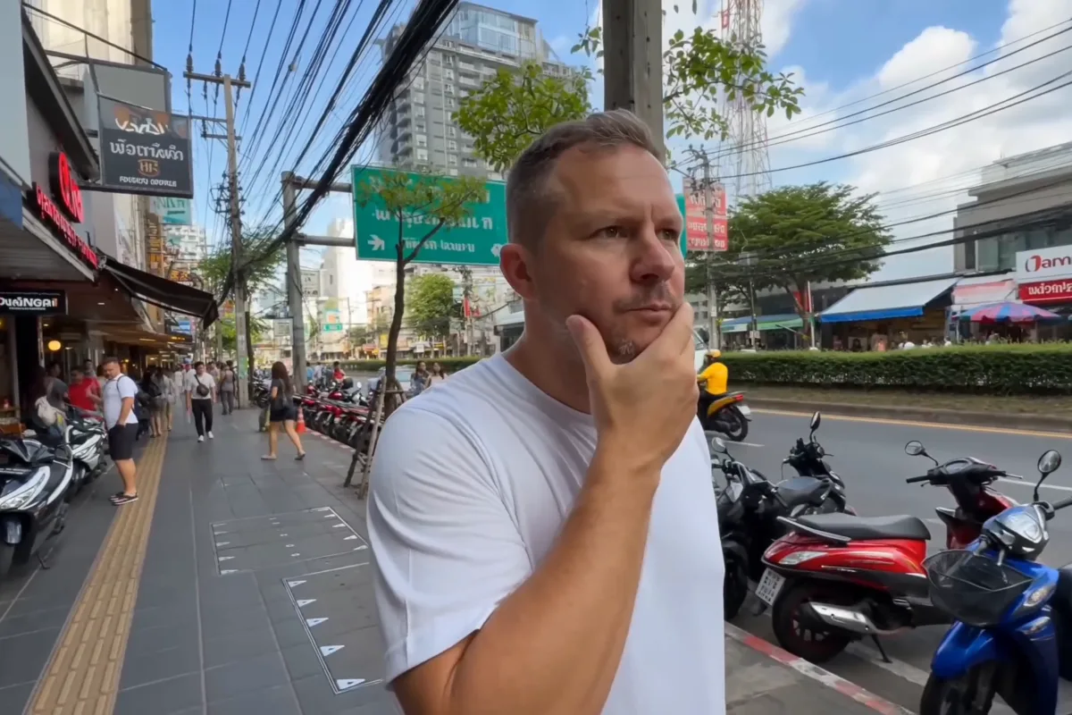 Eine Straße in Thonglor mit Motorrollern, Läden und Oberleitungen