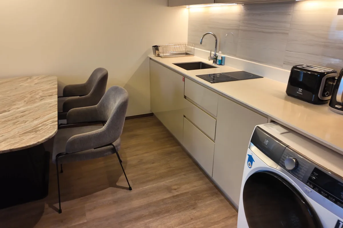 Küche mit Waschmaschine und Esstisch im 3-Schlafzimmer-Verbindungsapartment im Ascott Embassy Sathorn