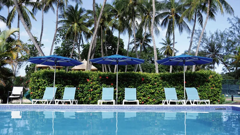 Pool mit blauen Sonnenschirmen und Palmen