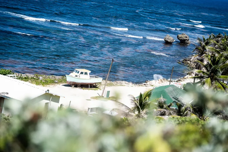 Atlantikküste mit Felsen, Palmen und einem Fischerboot an Land