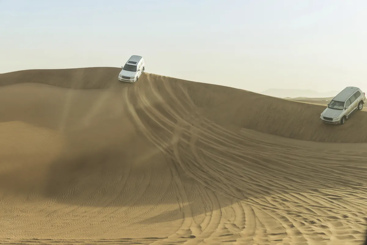 Zwei Geländewagen fahren über die Sanddünen der Wüste bei Dubai
