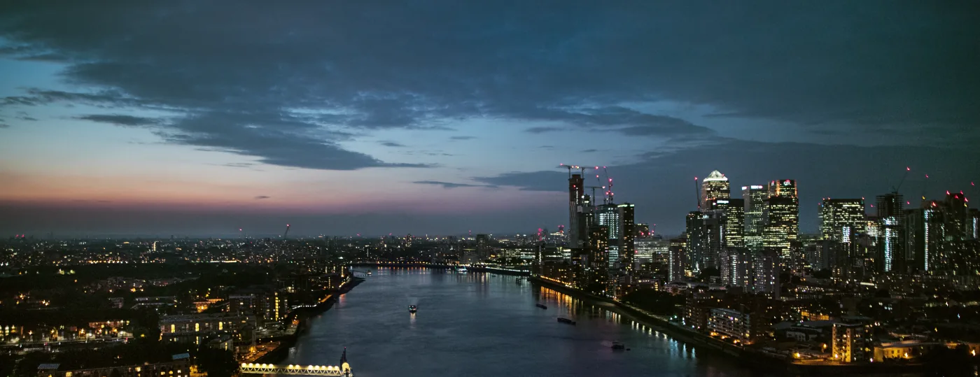 Die Themse bei Nacht mit den beleuchteten Hochhäusern von Canary Wharf
