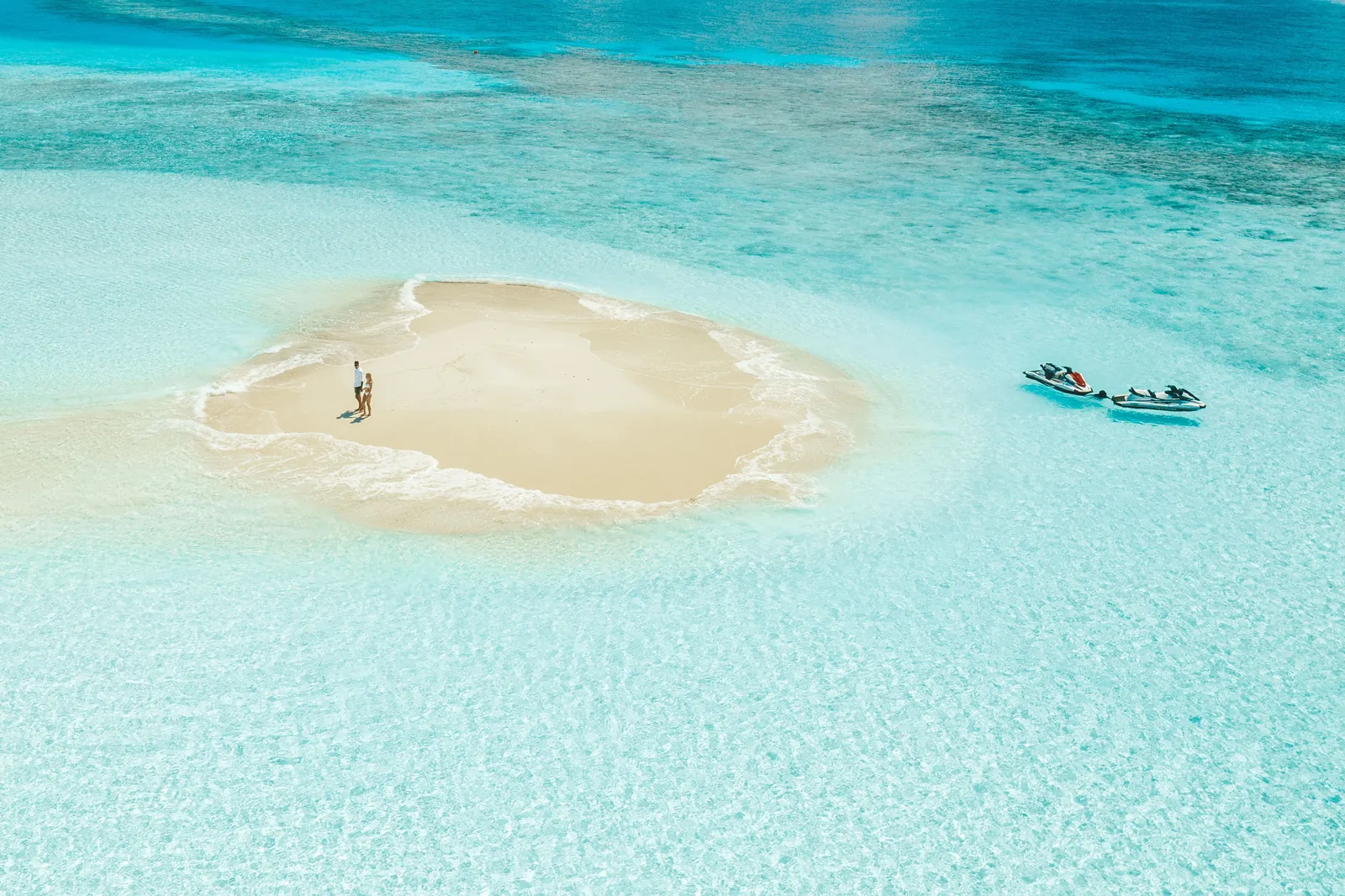 Ein Boot legt an einer Sandbank im türkisfarbenen Wasser der Malediven an