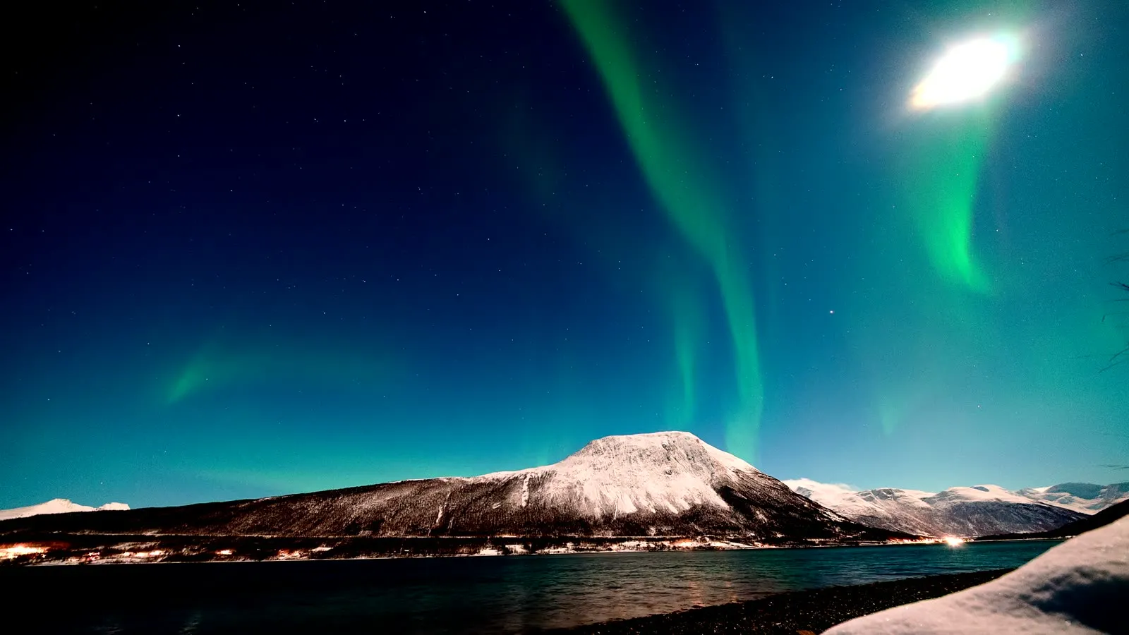 Nordlicht über einem verschneiten Fjord bei Nordkjosbotn in Nordnorwegen